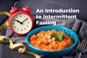 bowl of nutritious looking food in front of an analogue alarm clocks. Includes caption "an introduction to intermittent fasting"