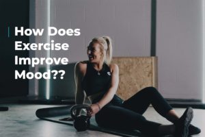 Smiling woman sat on floor surrounded by exercise equipment holding a kettlebell on the floor. Image includes the text "how does exercise improve mood?"
